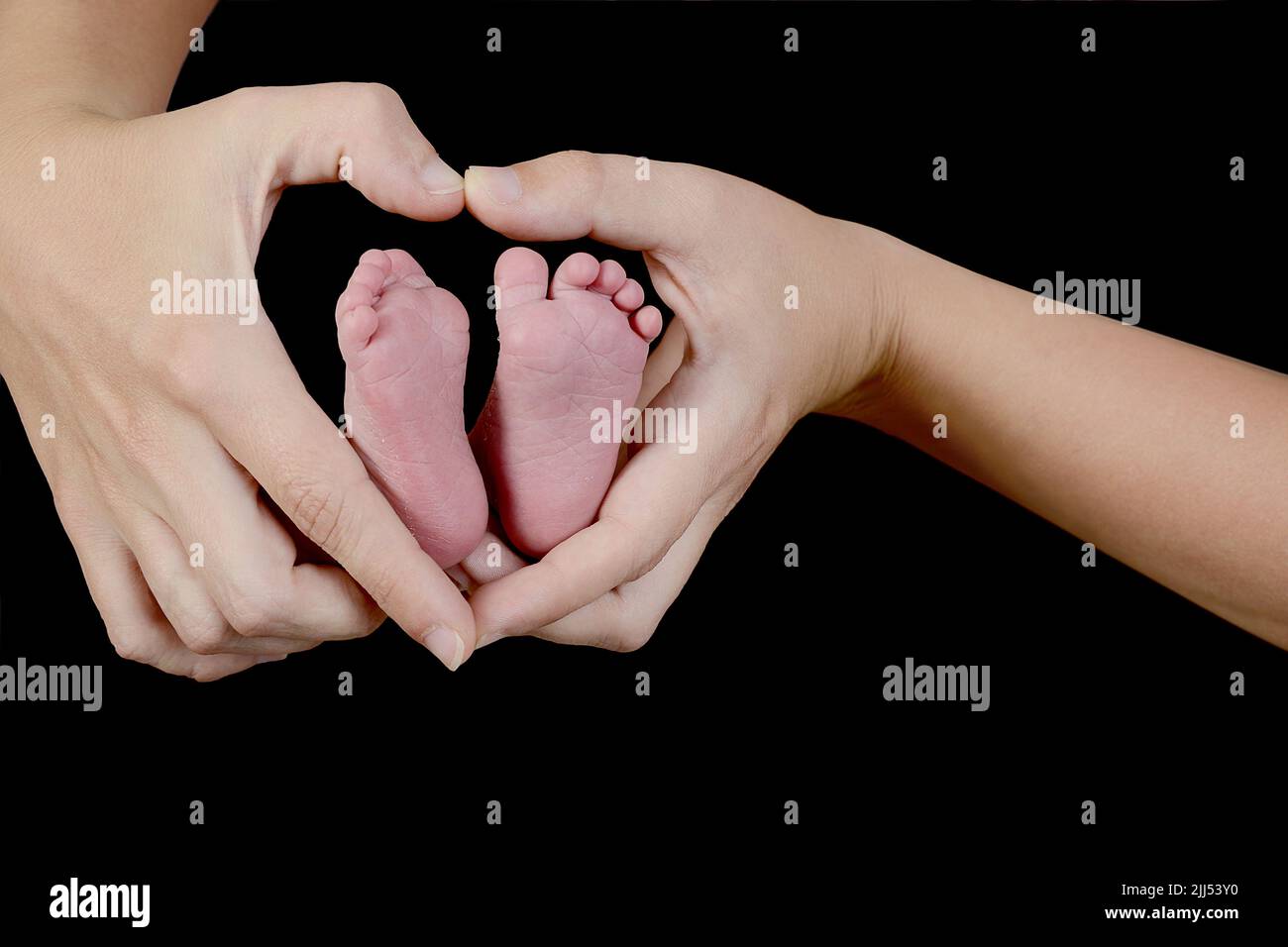 Les pieds du nouveau-né sont dans les mains en forme de cœur de sa mère. Concentrez-vous sur le pied et les mains sur la droite. Banque D'Images