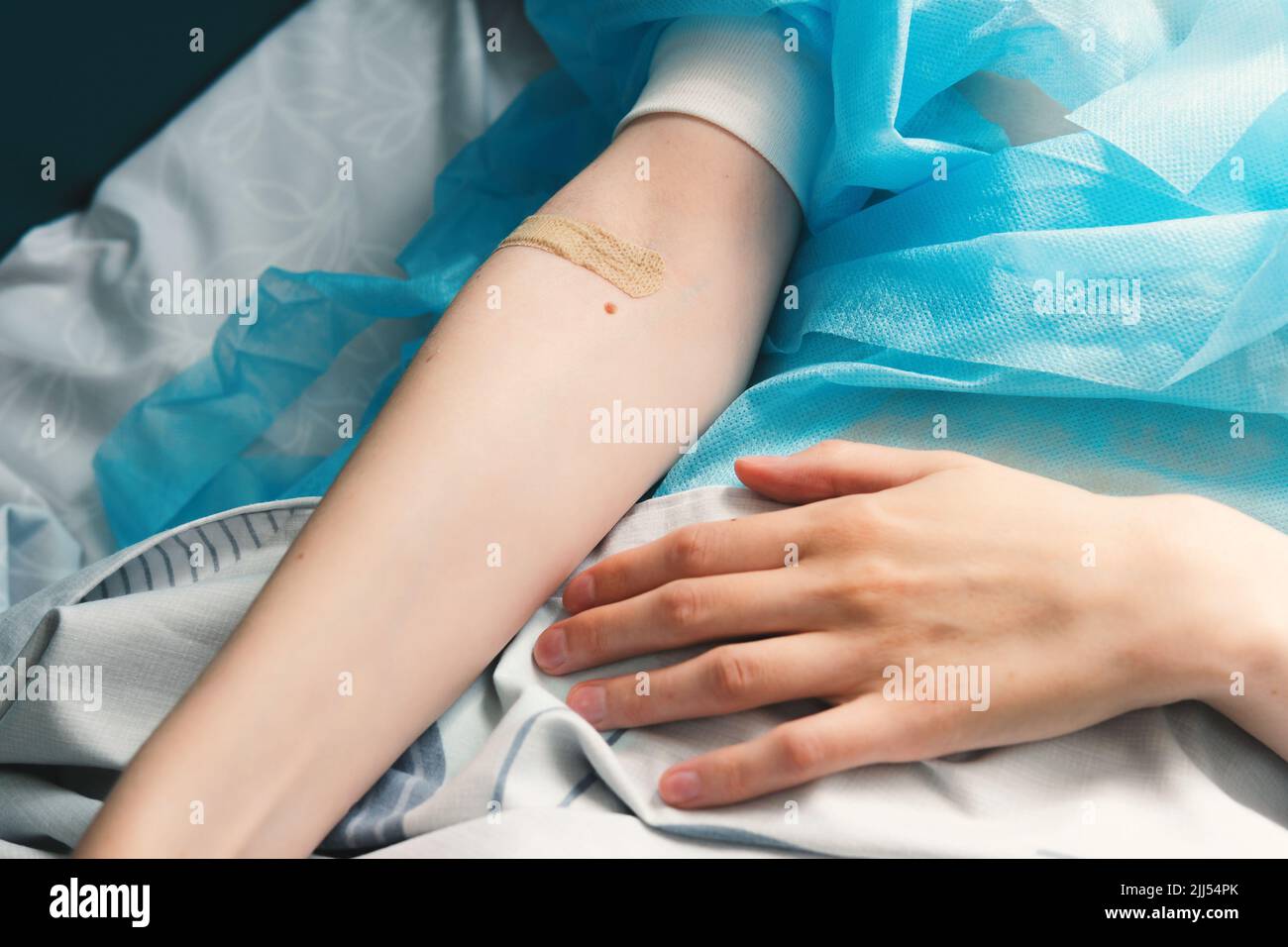 Gros plan de la main d'une femme avec un bracelet sur son bras. Patient allongé sur un lit d'hôpital après chirurgie. Banque D'Images