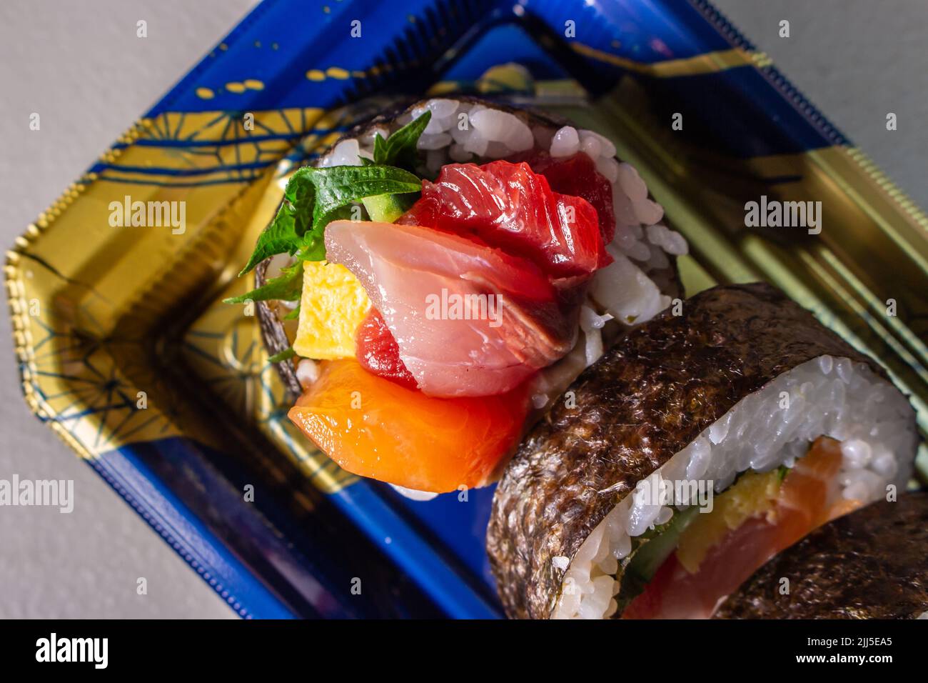Sortez le Kaisen Maki Zushi dans un plateau alimentaire en plastique Norimaki sur l'image, déployé par la feuille de shiso, le saumon, l'œuf frit (Tamago Yaki), le thon (Maguro) et le concombre Banque D'Images