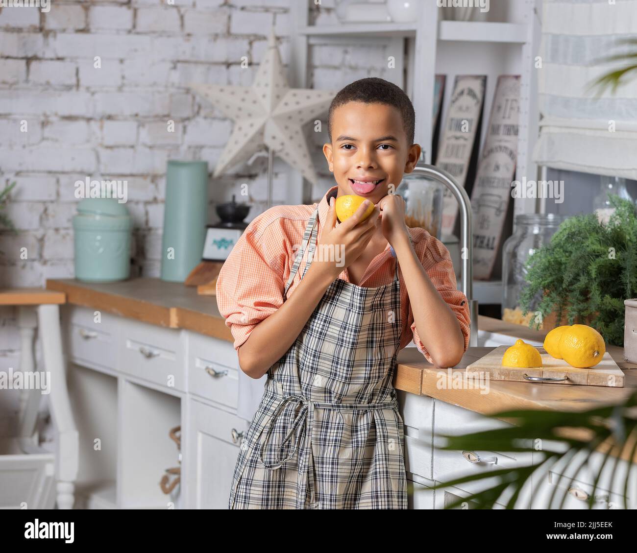 Enfant noir cuisant du citron frais dans la cuisine à la maison. Enfant africain se préparant sur la table. Banque D'Images