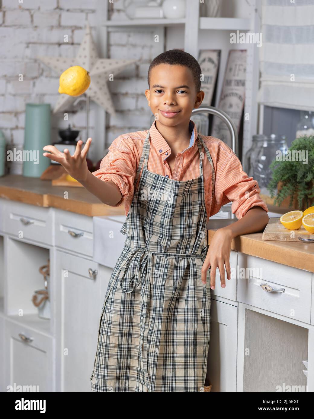Enfant noir cuisant du citron frais dans la cuisine à la maison. Enfant africain se préparant sur la table. Banque D'Images