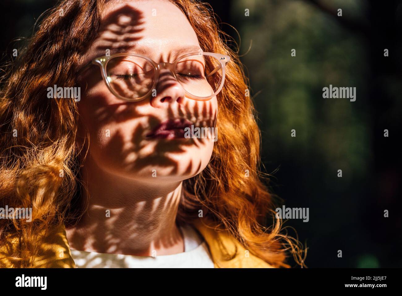 Femme avec les yeux fermés en profitant de la lumière du soleil Banque D'Images