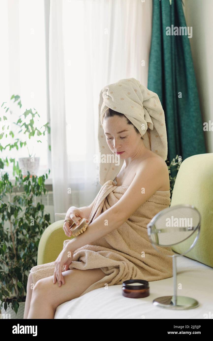 Femme massante avec une brosse sèche assise sur un canapé à la maison Banque D'Images