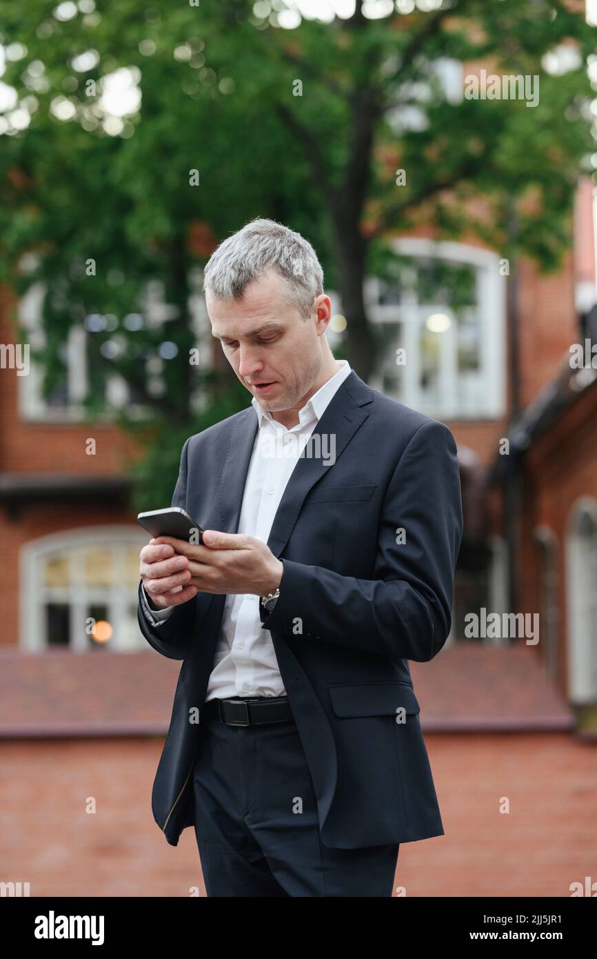 Homme d'affaires utilisant un smartphone debout dans la rue Banque D'Images
