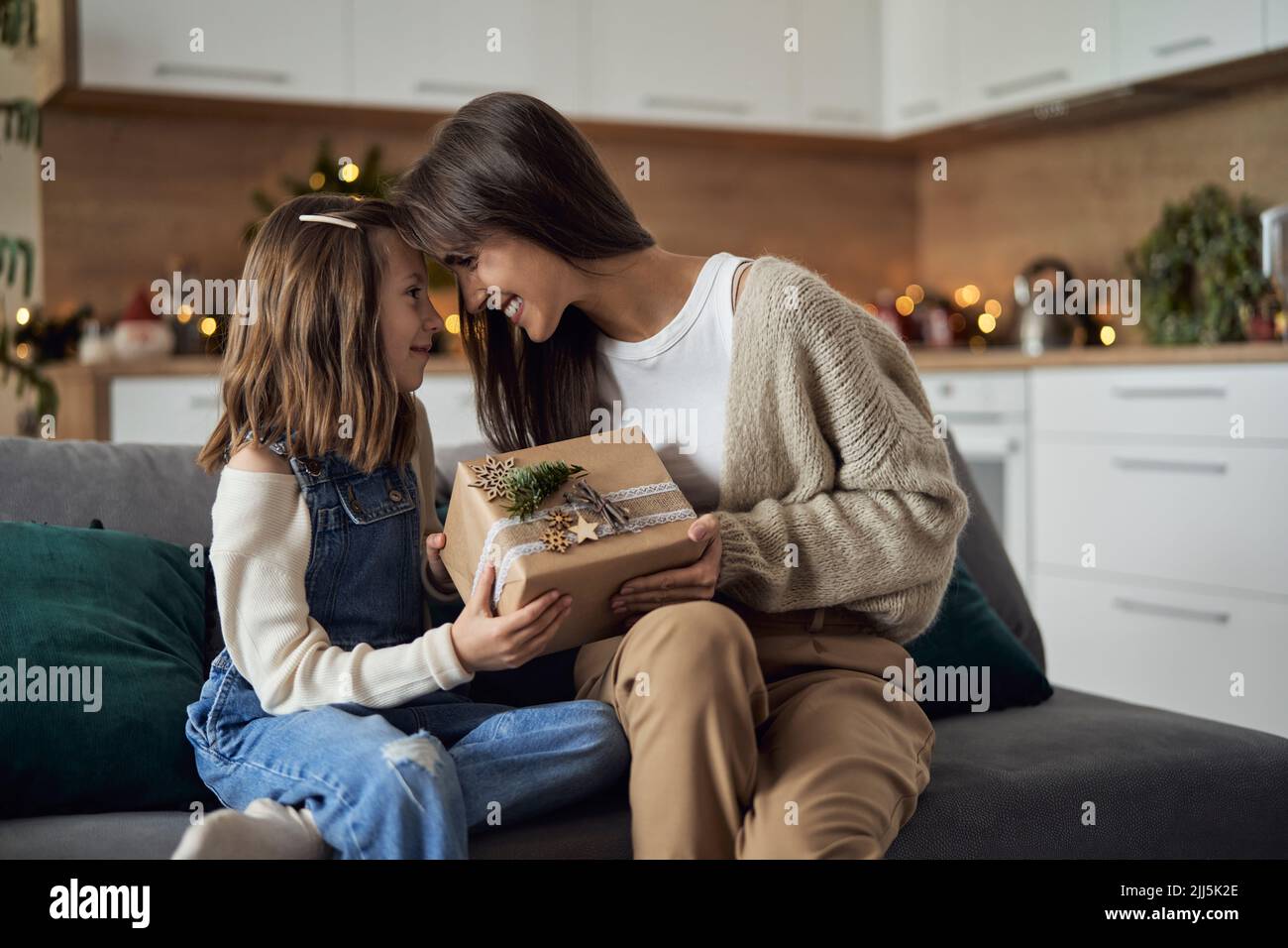 Femme souriante et fille partageant un cadeau de Noël entre elles à la maison Banque D'Images