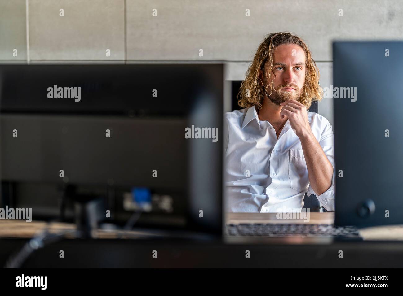 Siège de direction attentionné avec main sur le menton au bureau Banque D'Images