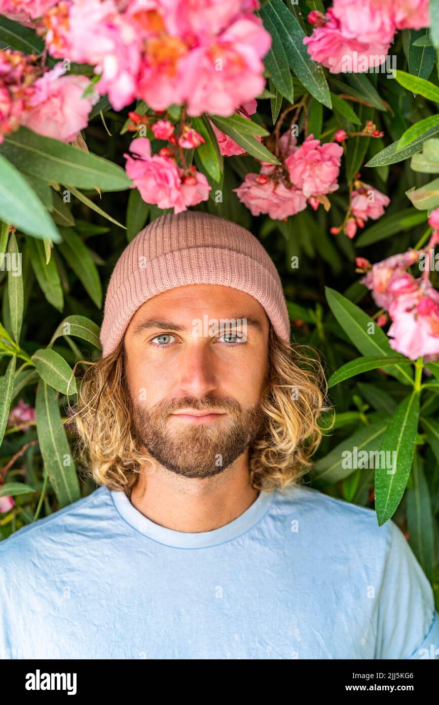 Homme portant un chapeau en tricot devant la plante à fleurs Banque D'Images