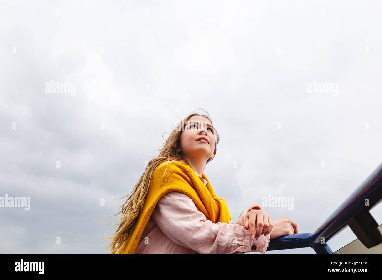 Jeune femme debout sous ciel nuageux Banque D'Images