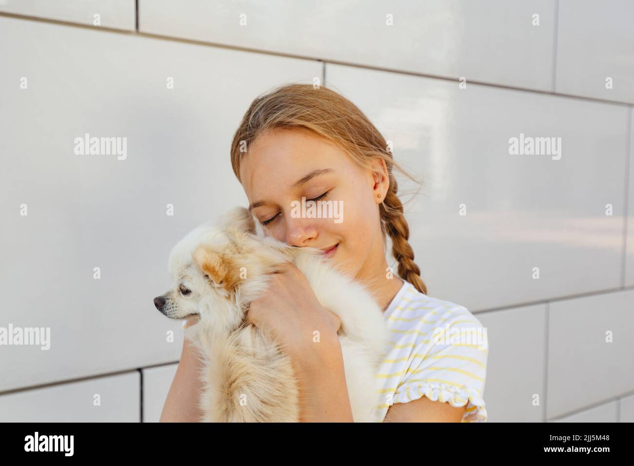 Fille souriante embrassant le chien devant le mur Banque D'Images