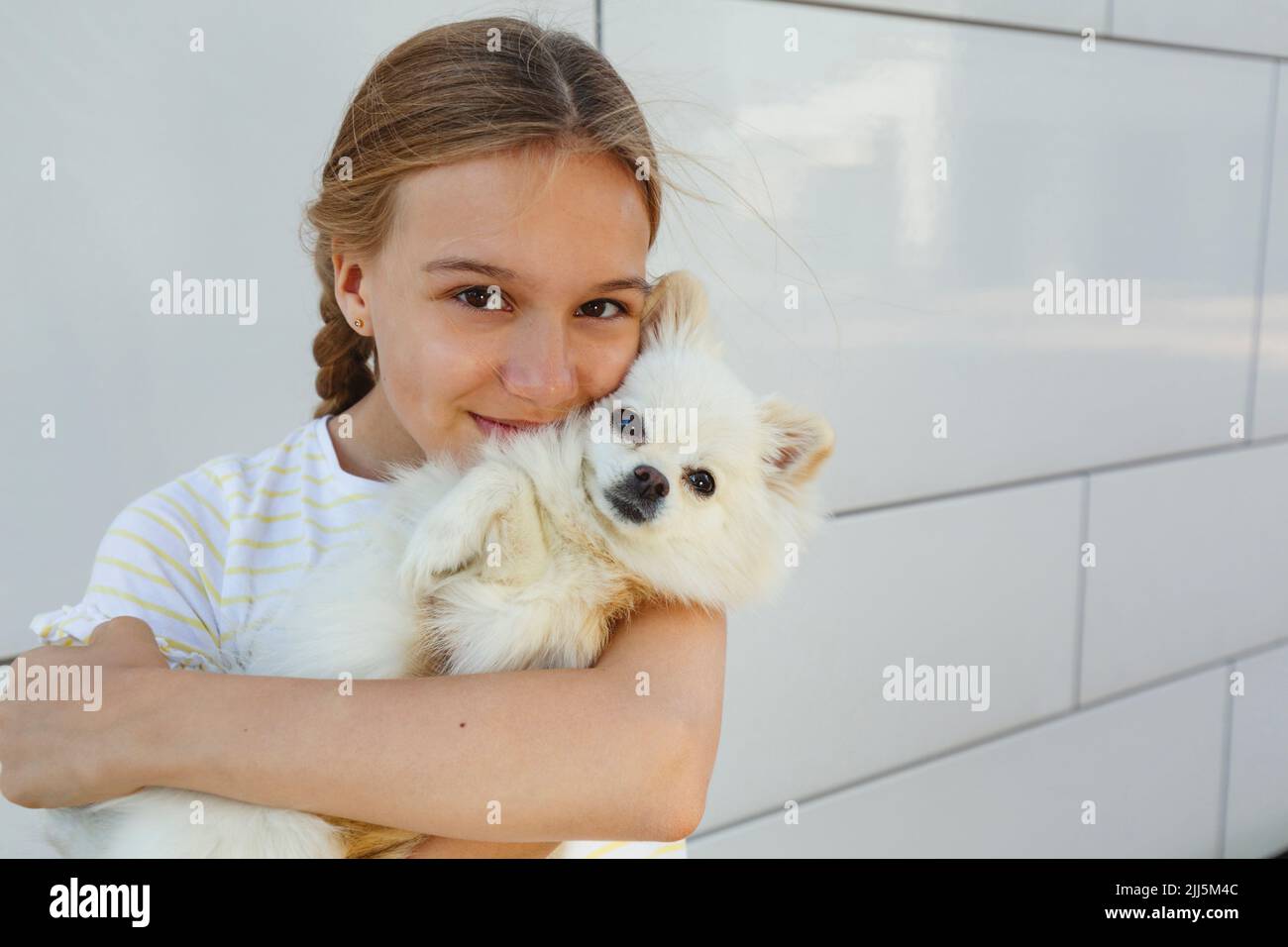 Bonne fille embrassant le chien devant le mur Banque D'Images