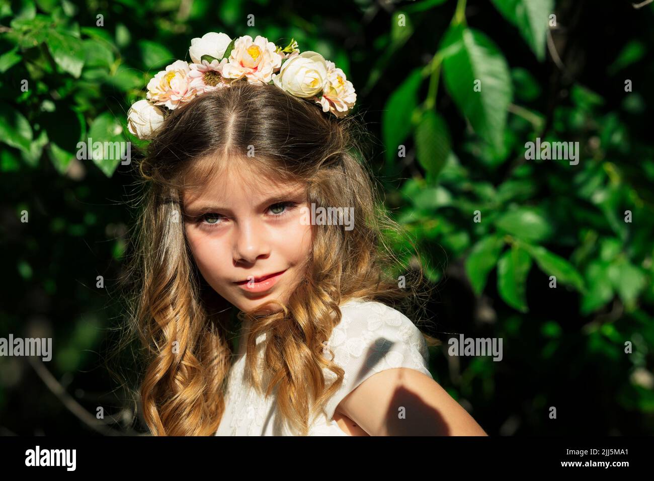 Fille souriante portant une couronne de fleur en forêt Banque D'Images