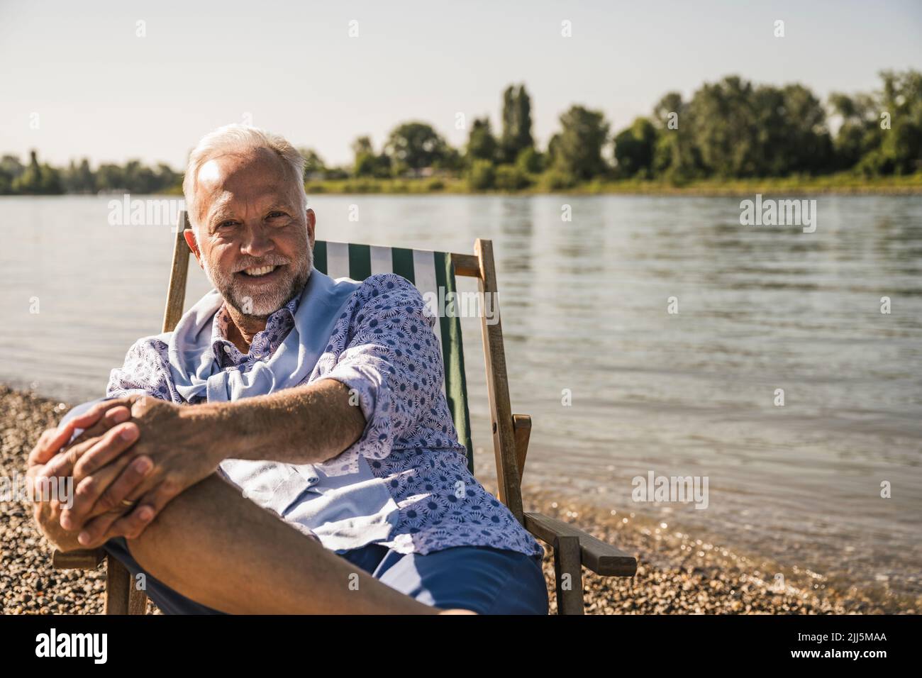 Homme senior souriant au bord de la rivière Banque D'Images
