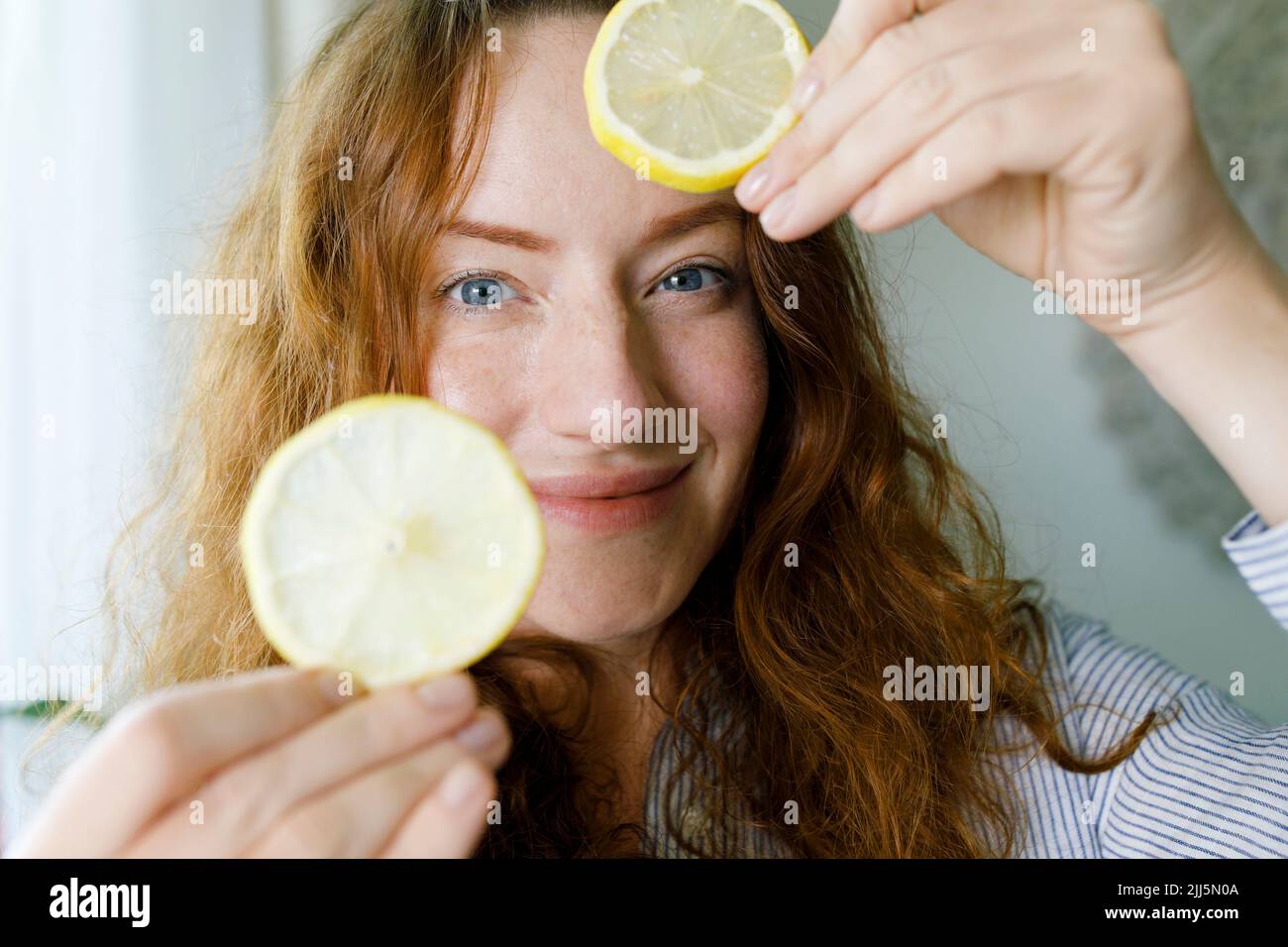 Femme souriante tenant des tranches de citron Banque D'Images