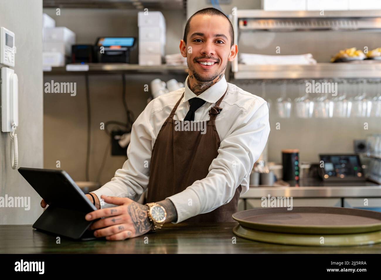 Barman souriant avec tablette PC au comptoir Banque D'Images