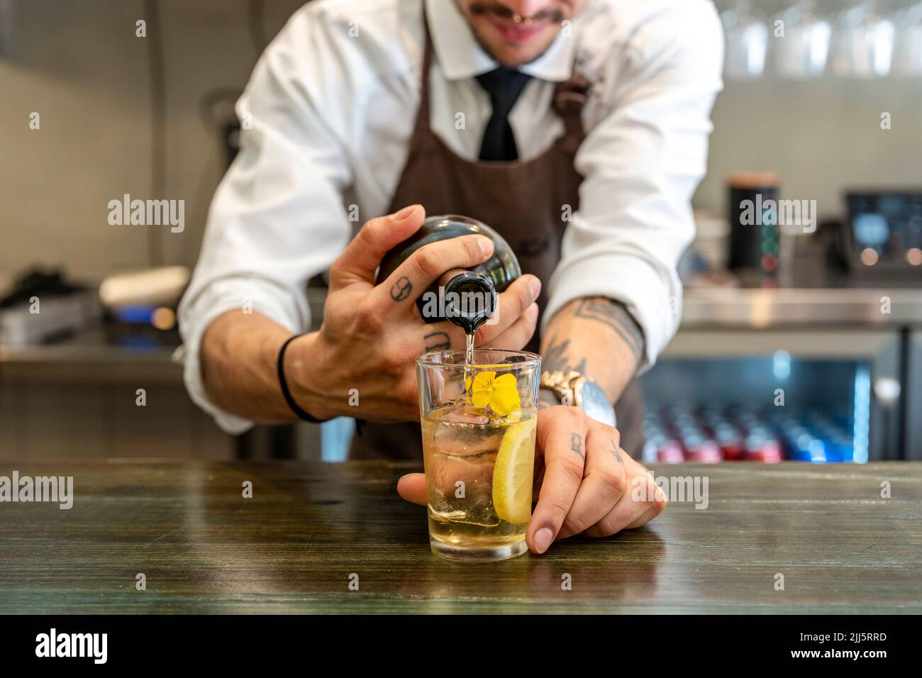 Le barman verse la boisson dans le verre au comptoir du bar Banque D'Images