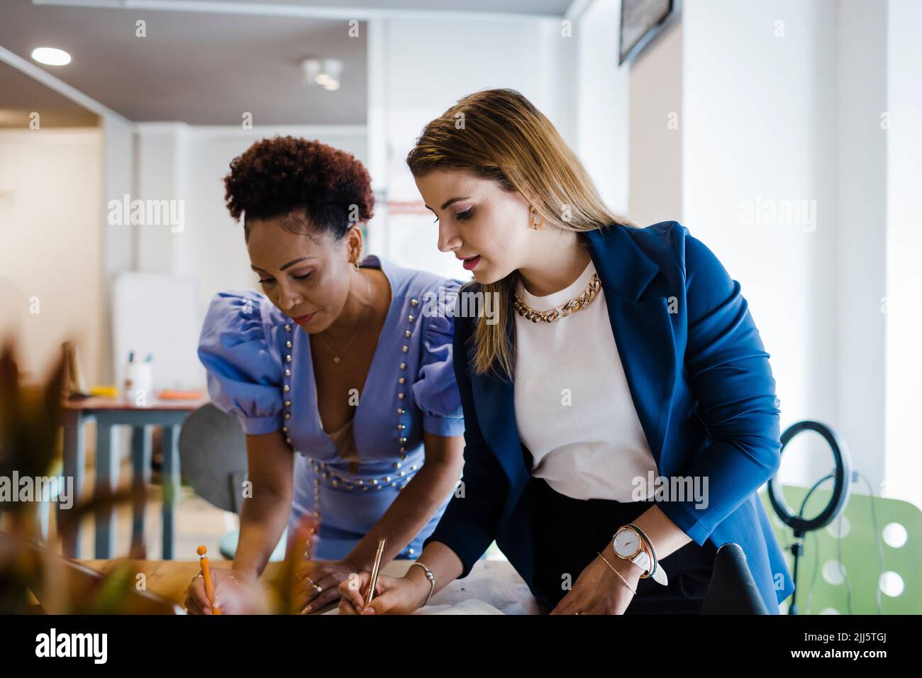 Femme d'affaires écrivant des notes avec un collègue au bureau Banque D'Images