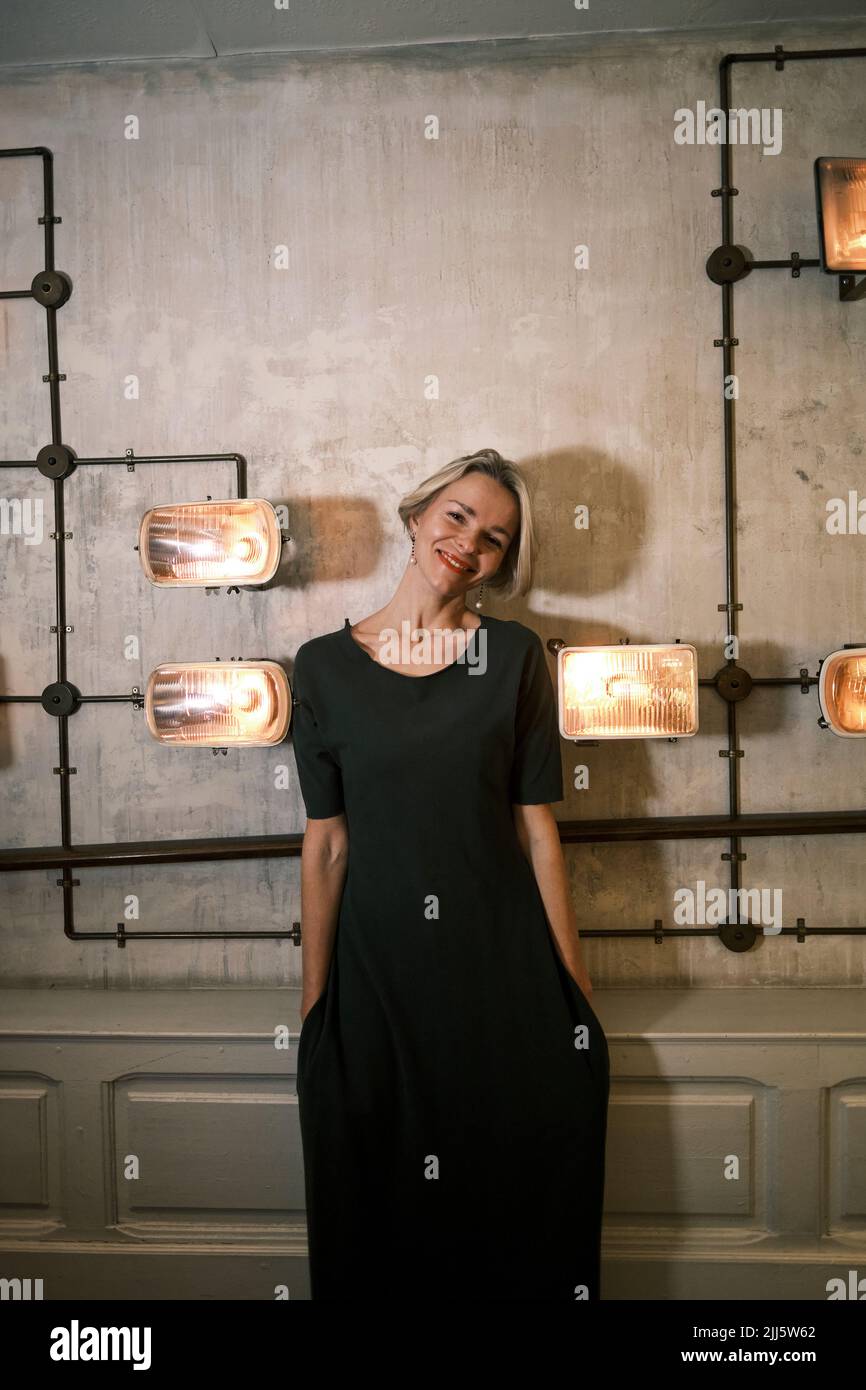 Femme heureuse avec les mains dans les poches debout au milieu des lumières illuminées Banque D'Images