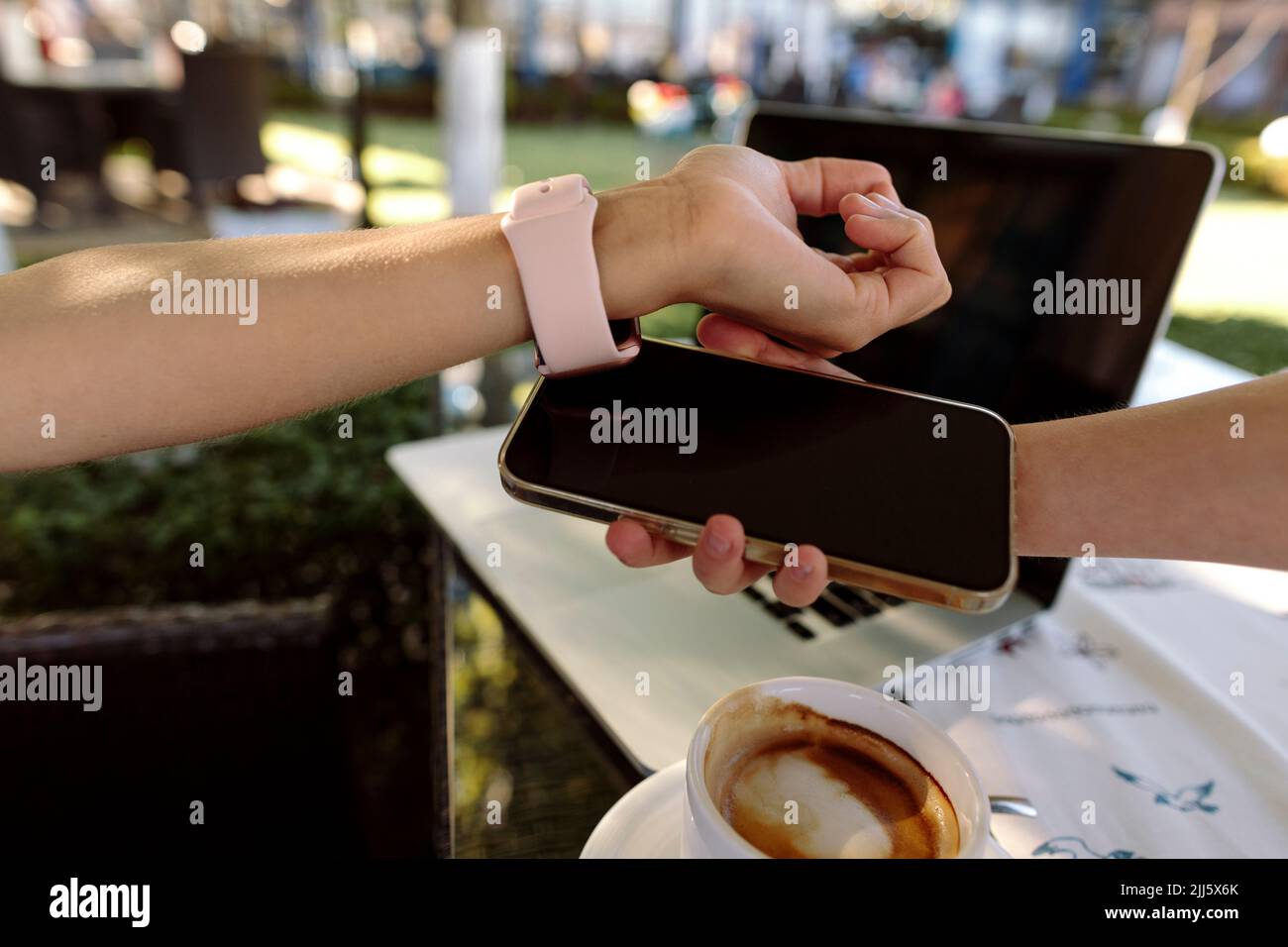 Femme qui paie par le biais d'une montre intelligente sur un téléphone portable tenu par un caissier Banque D'Images