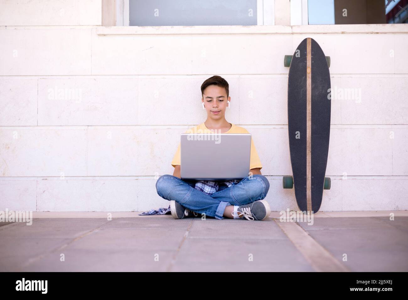 Adolescent du Caucase assis sur le sol à l'aide d'un ordinateur portable. Espace pour le texte. Banque D'Images