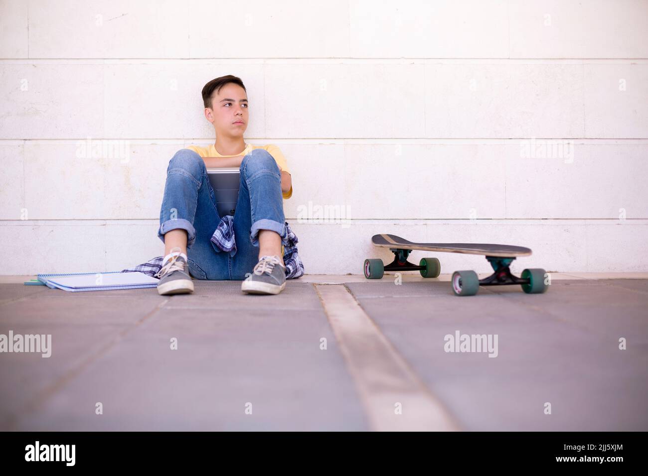 Adolescent caucasien garçon triste. Il est assis sur le plancher dans une attitude négative. Espace pour le texte. Banque D'Images