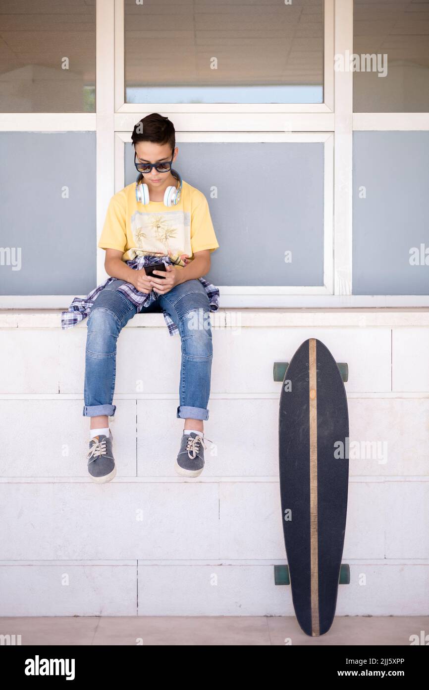 Jeune patineuse caucasienne utilisant un téléphone mobile à l'extérieur. Espace pour le texte. Banque D'Images