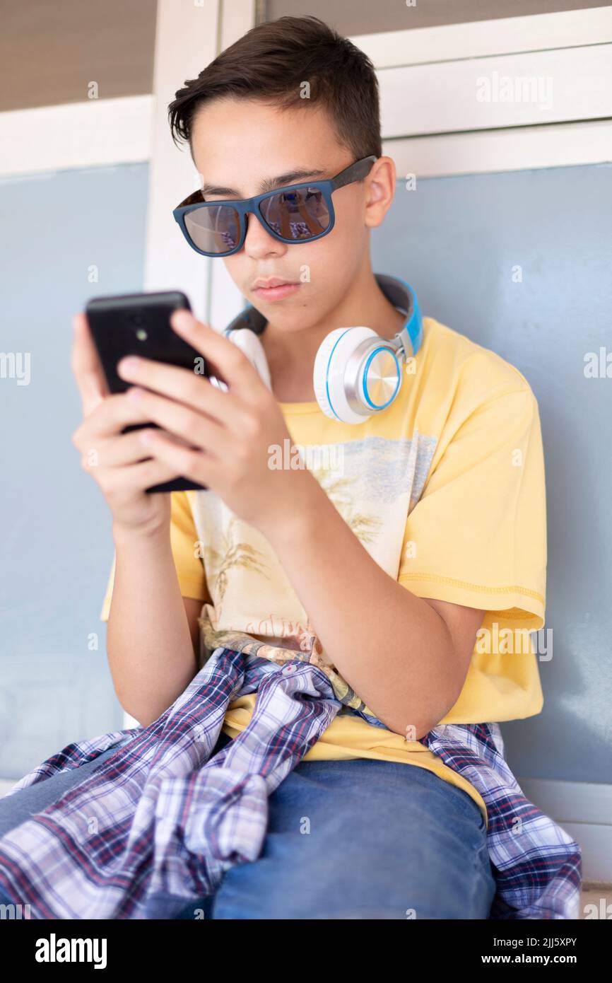 Portrait d'un adolescent du caucase à l'aide d'un téléphone portable. Il porte des vêtements décontractés. Banque D'Images