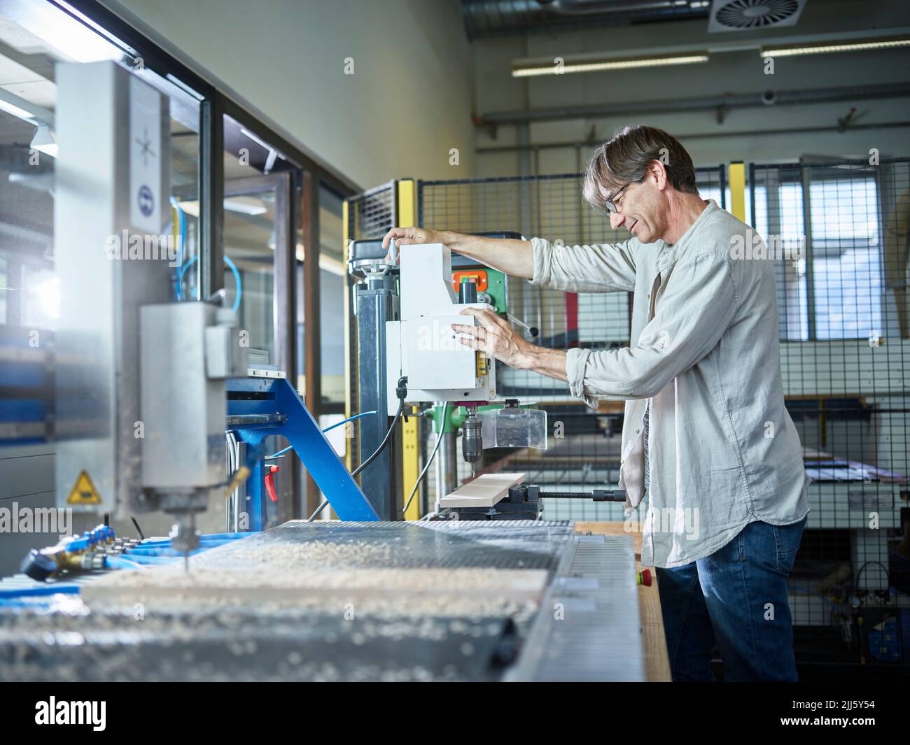 Homme mature travaillant sur une machine à bois en usine Banque D'Images