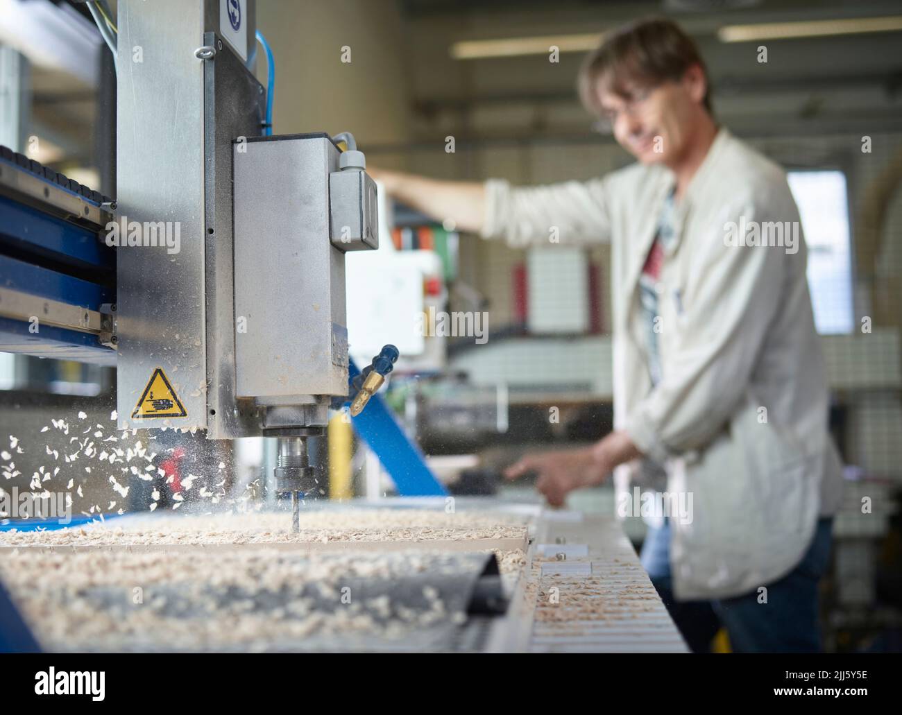 Homme mature avec machine CNC travaillant en usine Banque D'Images