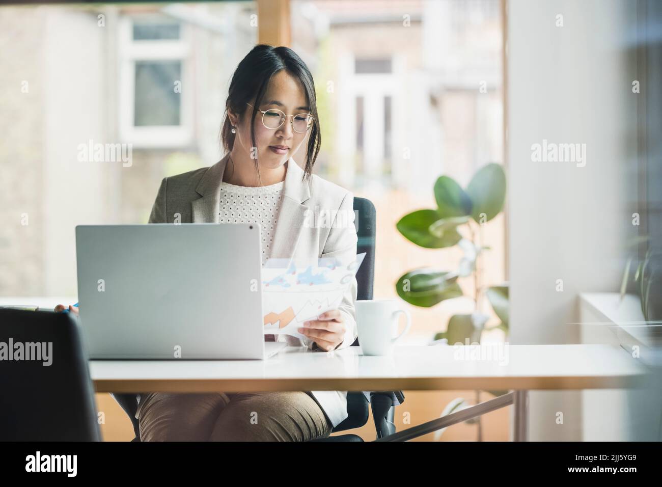 Femme d'affaires avec des documents assis au bureau Banque D'Images