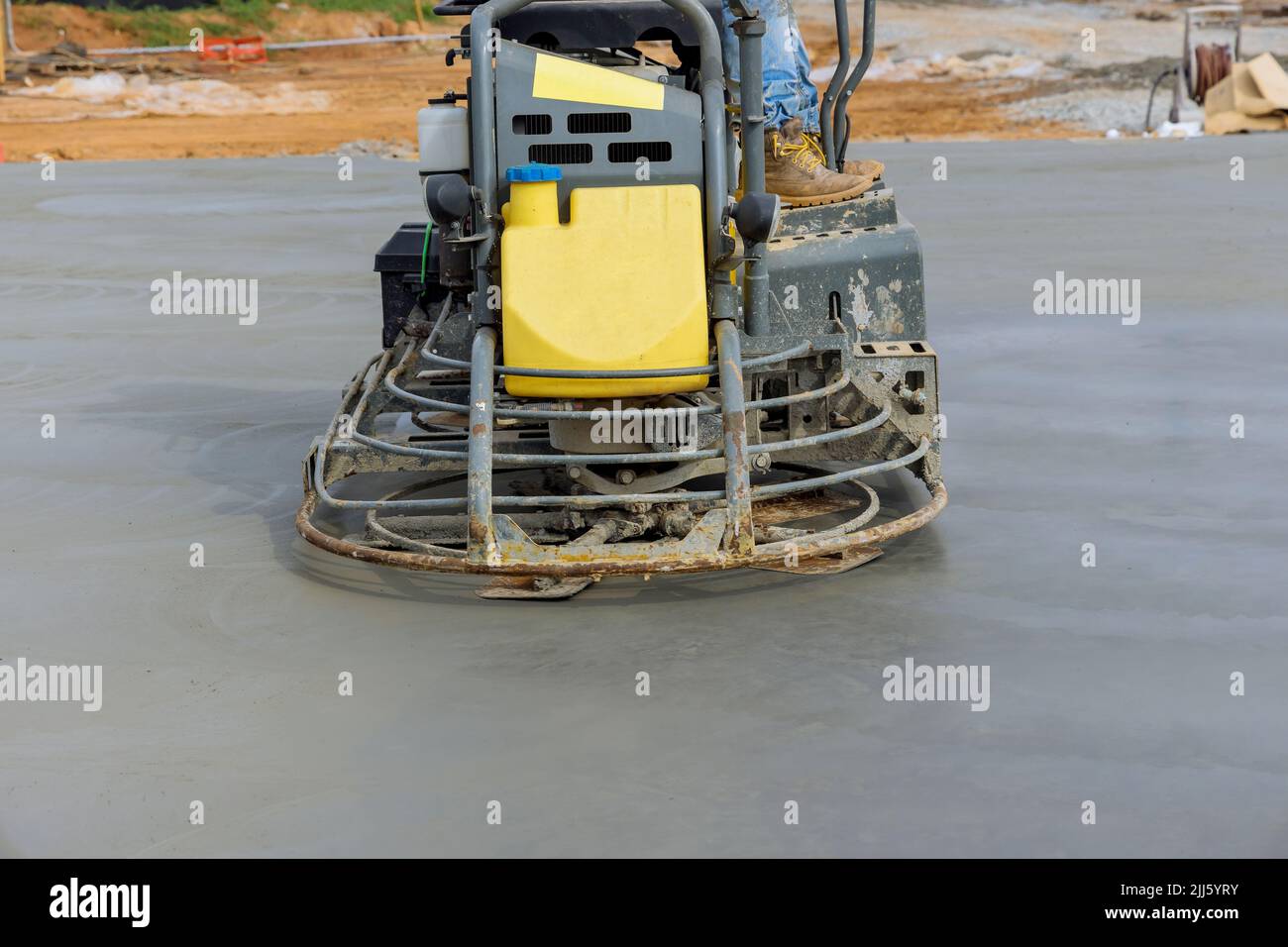 Des machines de polissage du béton sont utilisées par les travailleurs pour polir le ciment après qu'il a été versé sur le plancher de fondation Banque D'Images