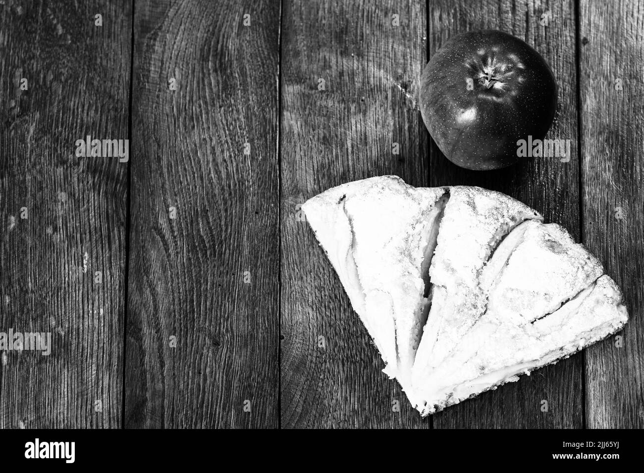 Tranches de tarte aux pommes fraîchement cuits au four avec du sucre en poudre et de pomme rouge sur une planche de bois. Gâteau aux pommes maison. Banque D'Images