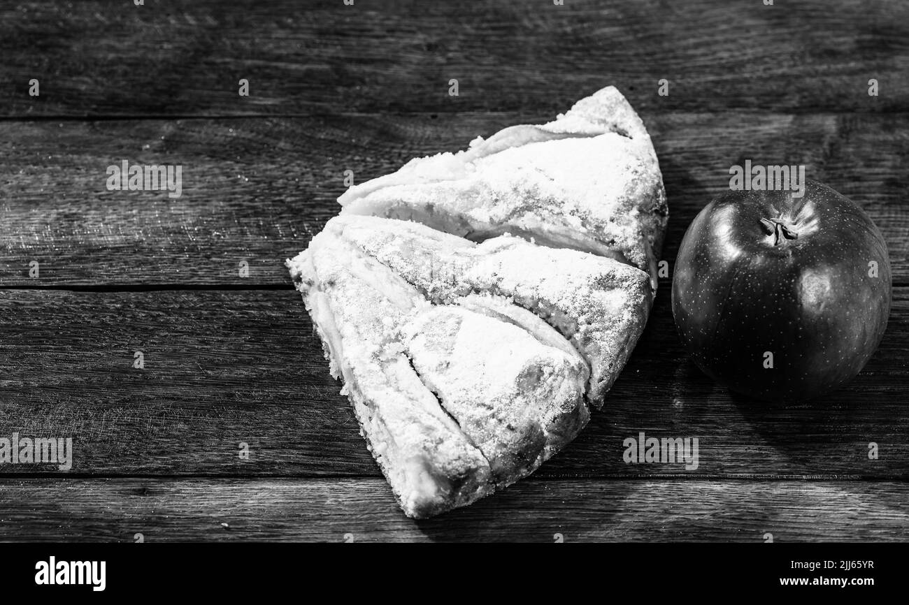 Tranches de tarte aux pommes fraîchement cuits au four avec du sucre en poudre et de pomme rouge sur une planche de bois. Gâteau aux pommes maison. Banque D'Images