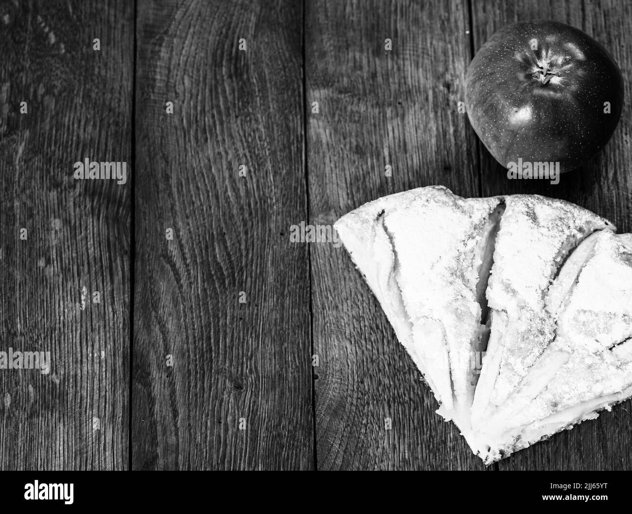 Tranches de tarte aux pommes fraîchement cuits au four avec du sucre en poudre et de pomme rouge sur une planche de bois. Gâteau aux pommes maison. Banque D'Images