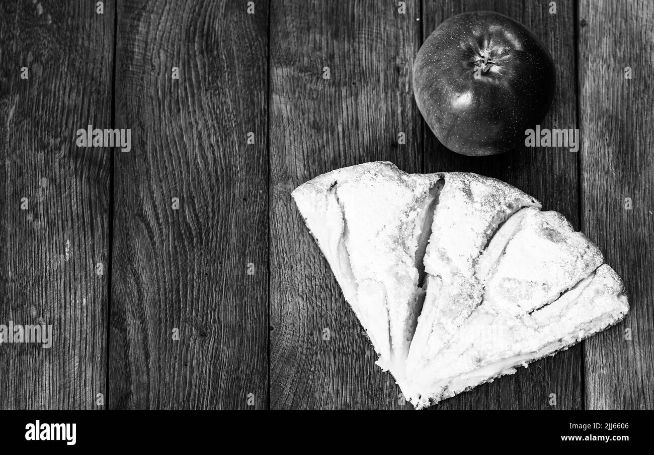 Tranches de tarte aux pommes fraîchement cuits au four avec du sucre en poudre et de pomme rouge sur une planche de bois. Gâteau aux pommes maison. Banque D'Images