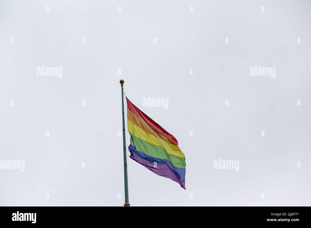 Gros plan sur le drapeau de fierté gay arc-en-ciel à l'extérieur dans une rue. Symbole de la communauté LGBT lesbienne bisexuelle transgenre agitant dans le vent contre un ciel nuageux. Soci Banque D'Images