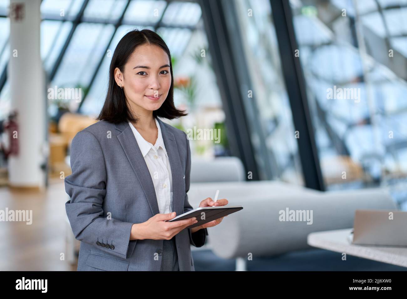 Jeune femme d'affaires asiatique souriante tenant une tablette numérique au bureau. Banque D'Images