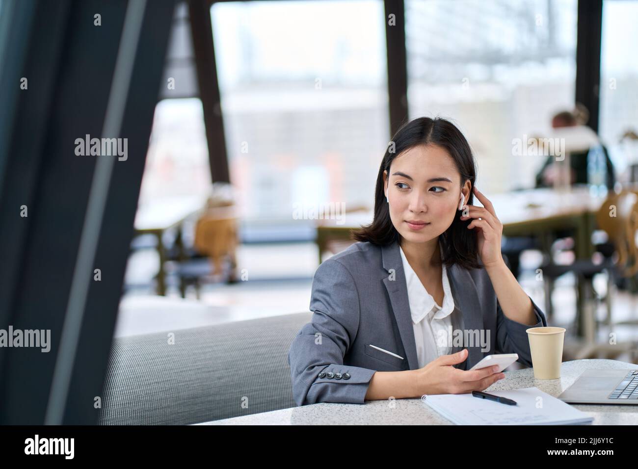 Jeune femme d'affaires asiatique utilisant un smartphone travaillant dans un bureau moderne. Banque D'Images