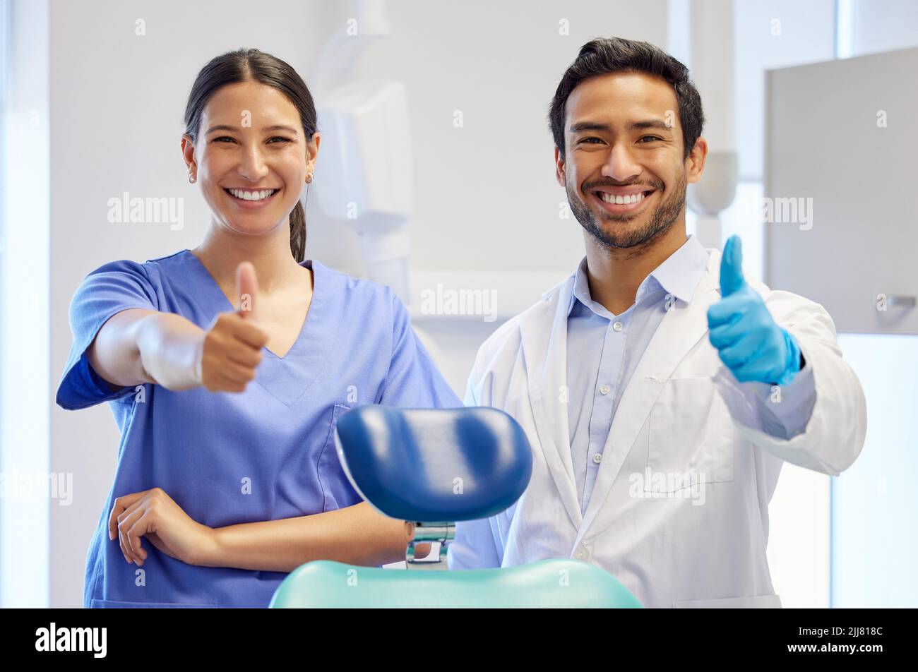 Eh bien, vos dents ont l'air bien. Portrait de deux jeunes dentistes montrant leurs pouces dans leur salle de conseil. Banque D'Images