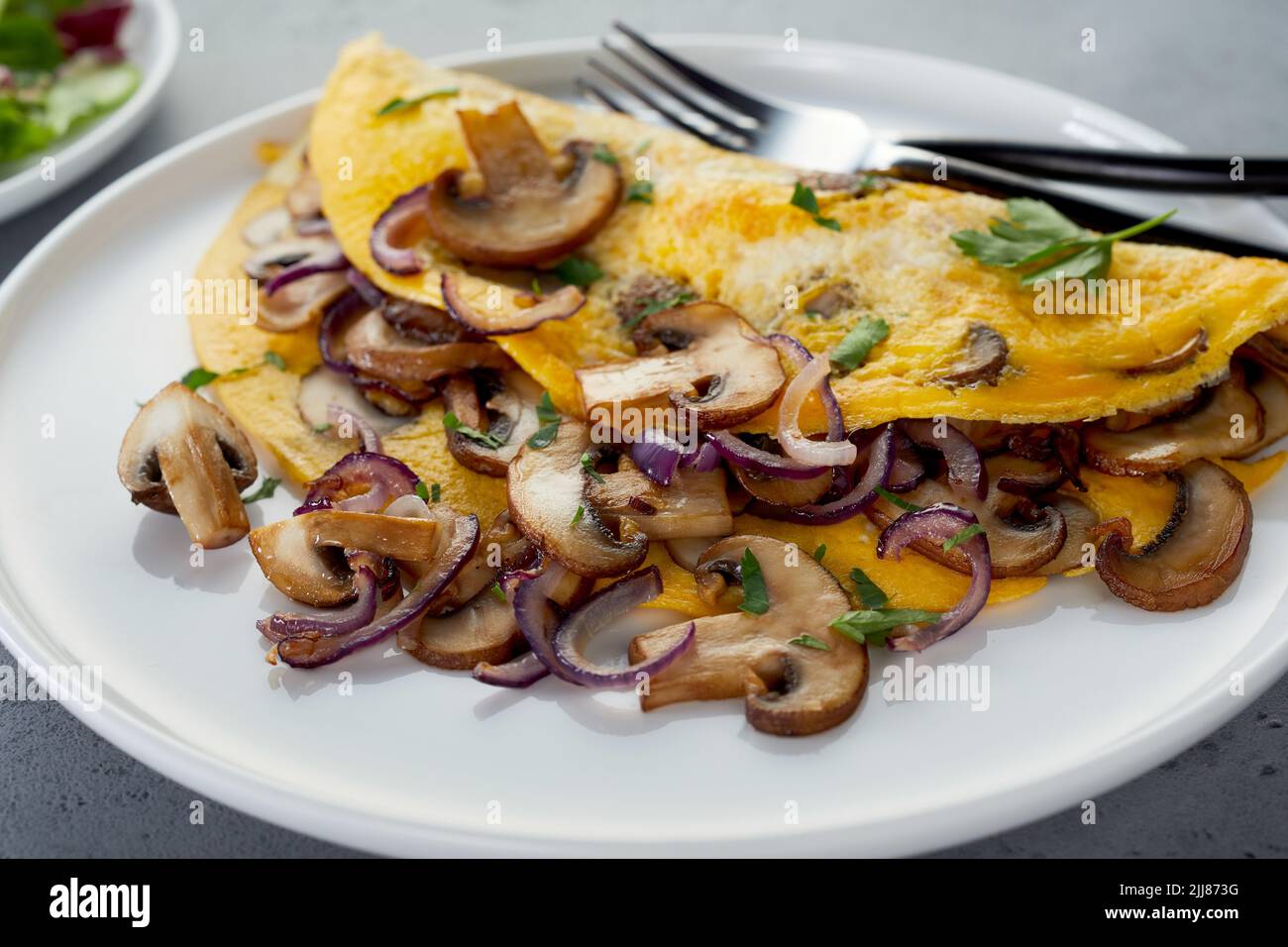 Omelette maison délicieuse avec champignons et oignons servis sur une assiette à table pour le déjeuner Banque D'Images