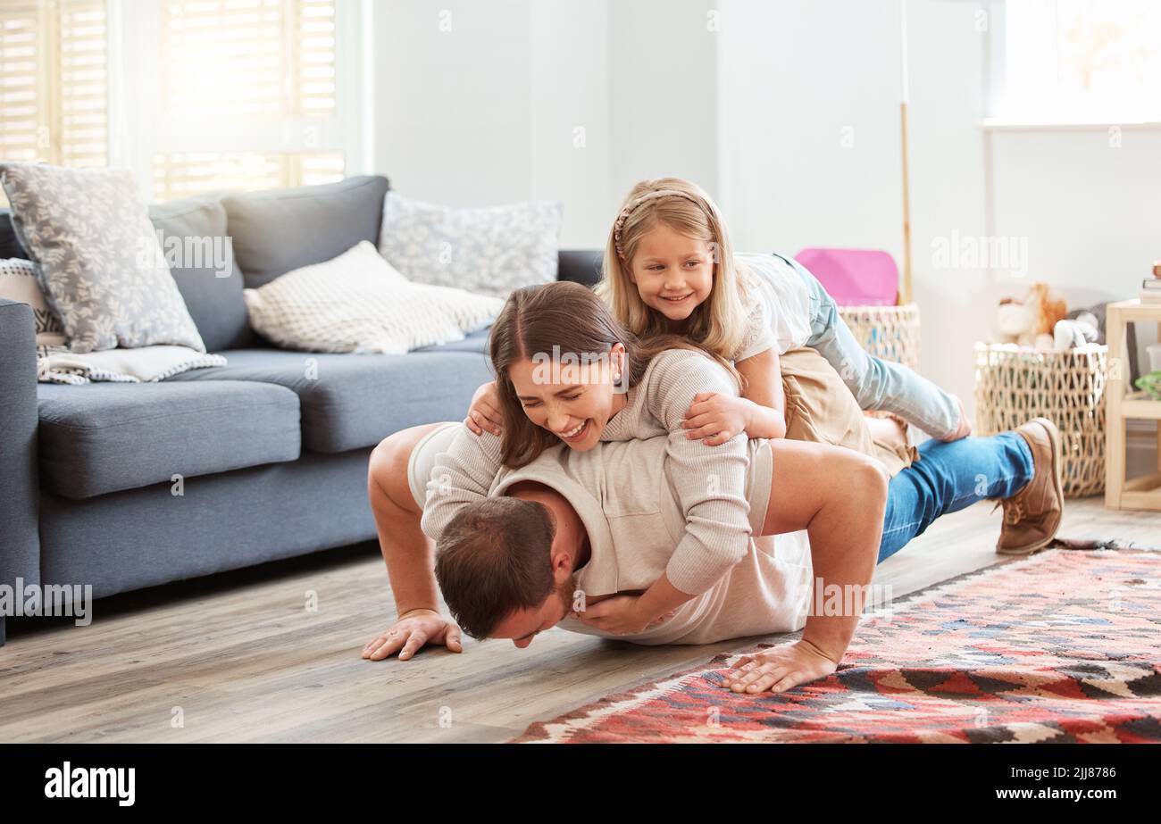 Combien pouvez-vous gérer. Un jeune père qui fait des poussettes avec sa femme et sa fille sur son dos à la maison. Banque D'Images
