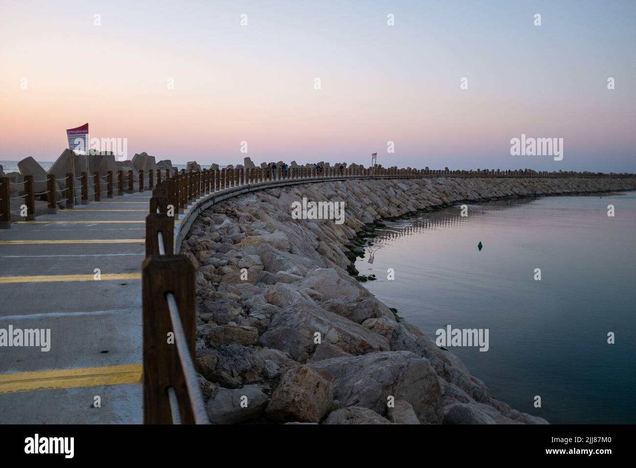 Vue sur une jetée près d'un port en bord de mer au coucher du soleil. Banque D'Images