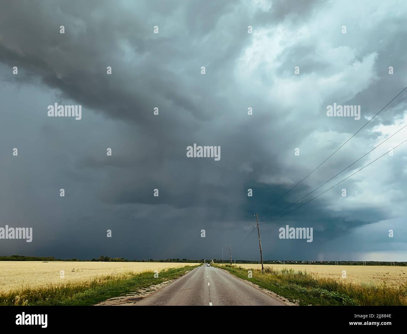 Tempête de nuages sur la route ou la route et les champs asphaltés. Banque D'Images