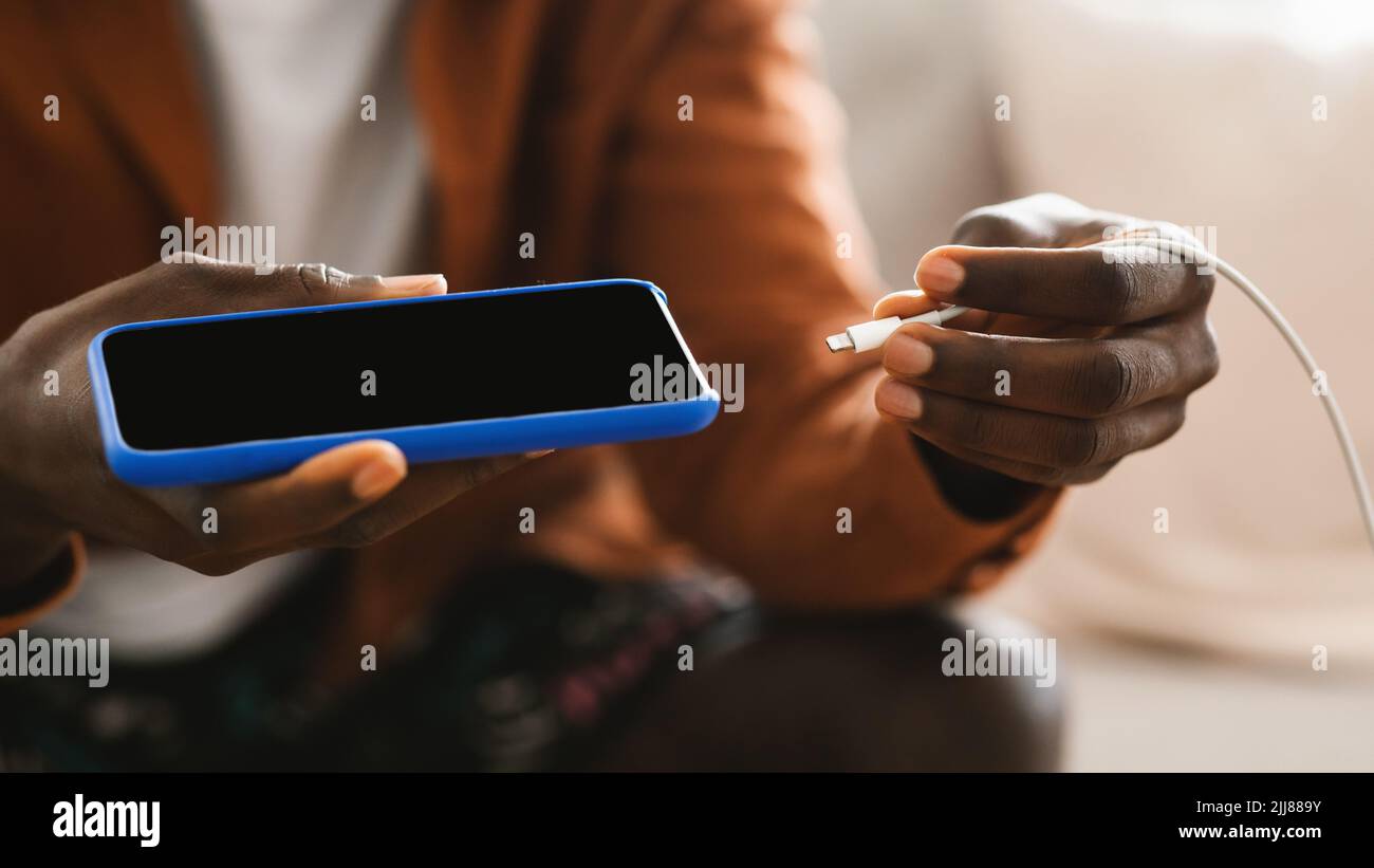 Mains mâles noires brancher un chargeur dans un smartphone moderne, à l'aide de powerbank, gros plan Banque D'Images