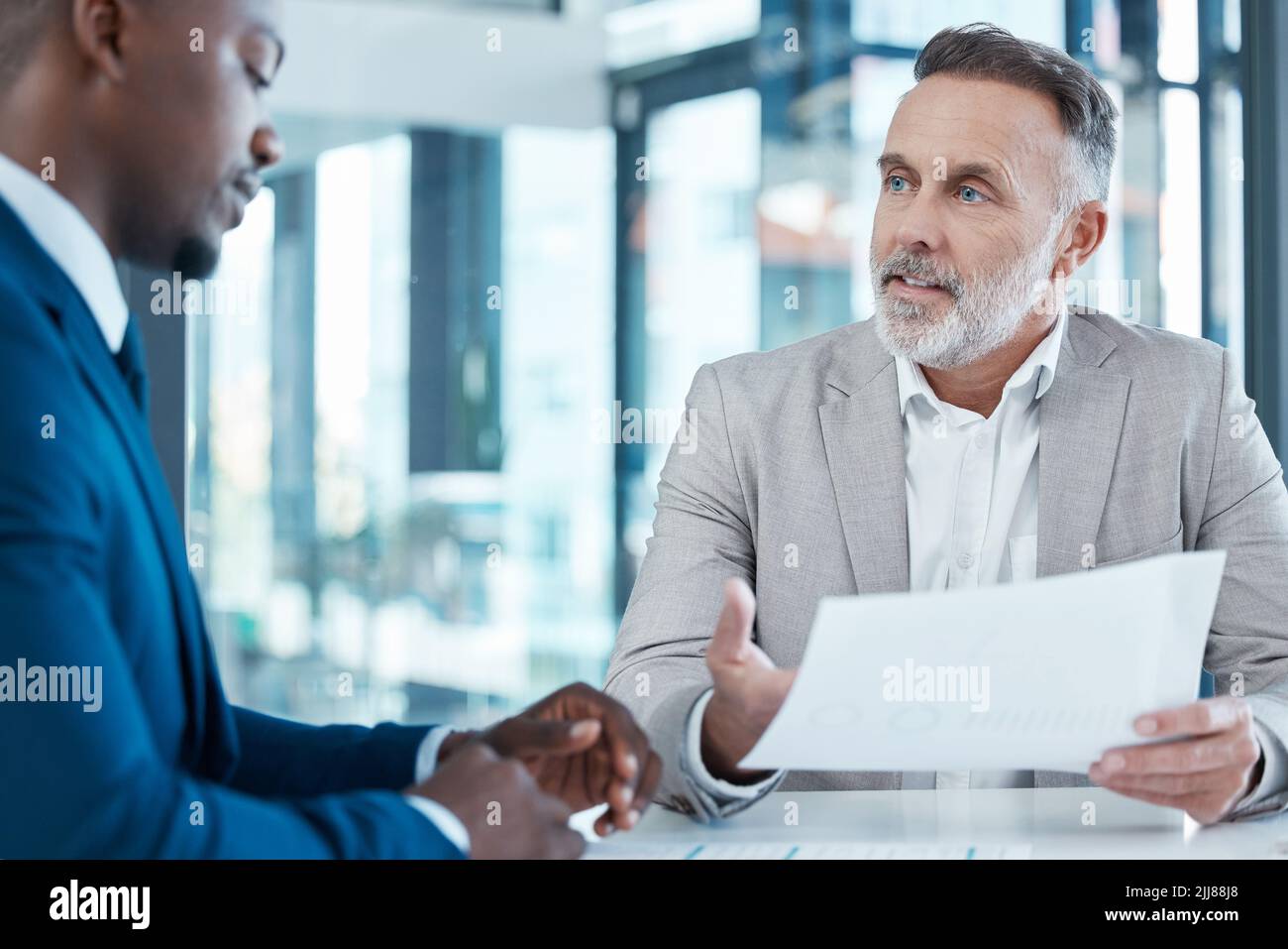 Les plus grands sorciers de la finance au monde : deux hommes d'affaires discutent de la paperasserie dans un bureau moderne. Banque D'Images