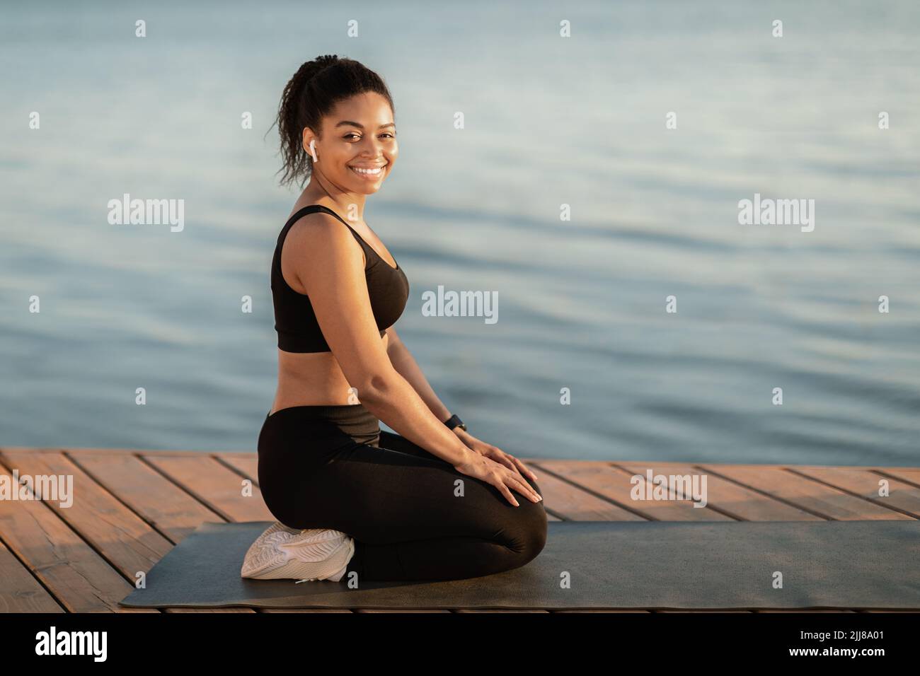 Femme afro-américaine paisible pratiquant le yoga sur la plage Banque D'Images