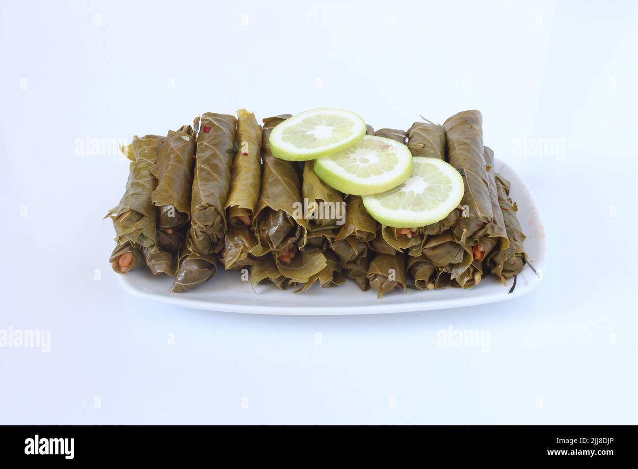 Cuisine turque ou grecque nourriture Yaprak Sarma (enveloppé farci) avec des tranches de citron. Feuilles de raisin farcies au riz isolées sur fond blanc. Banque D'Images