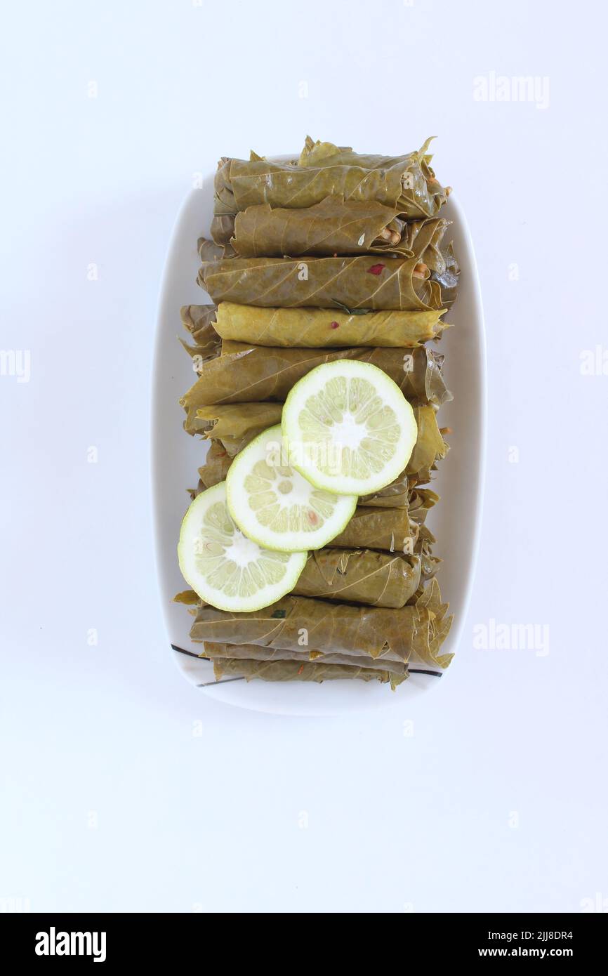 Cuisine turque ou grecque nourriture Yaprak Sarma (enveloppé farci) avec des tranches de citron. Feuilles de raisin farcies au riz isolées sur fond blanc. Banque D'Images