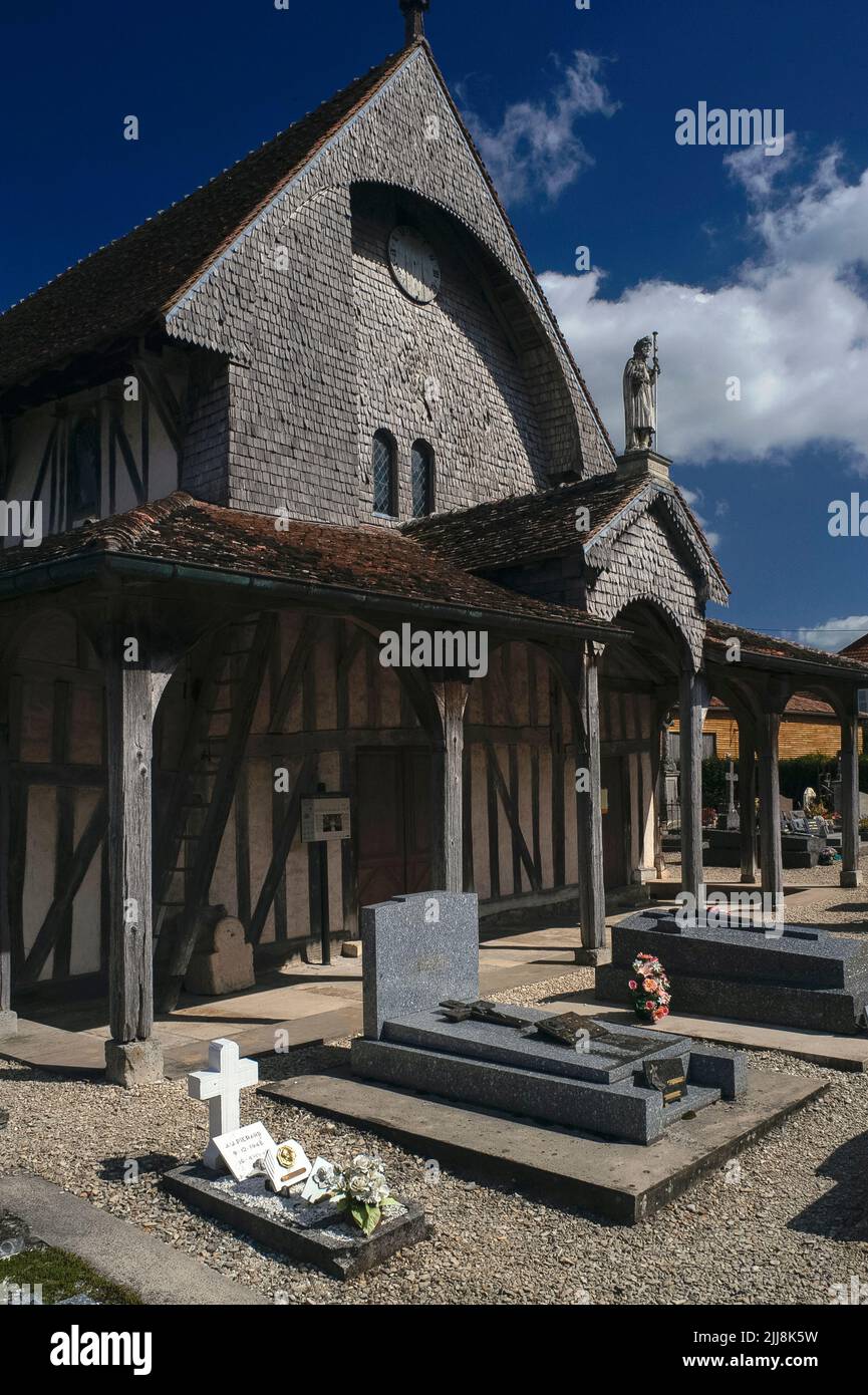 Une statue en pierre de l'Apôtre Saint-Jacques-et-Saint-Philippe se dresse au sommet du porche ouest en bois de l'église Saint-Jacques-et-Saint-Philippe à Lentilles, dans le pays du Der de l'Aube, dans le Grand-est, en France. L'église, fondée vers 1512, est un exemple typique des églises historiques à colombages ou à pans de bois de la région de Champagne, avec d'énormes poutres en chêne soutenant ses toits de tuiles rouges. Des bardeaux en bois pladaient également le pignon ouest et un beffroi octogonal. Banque D'Images