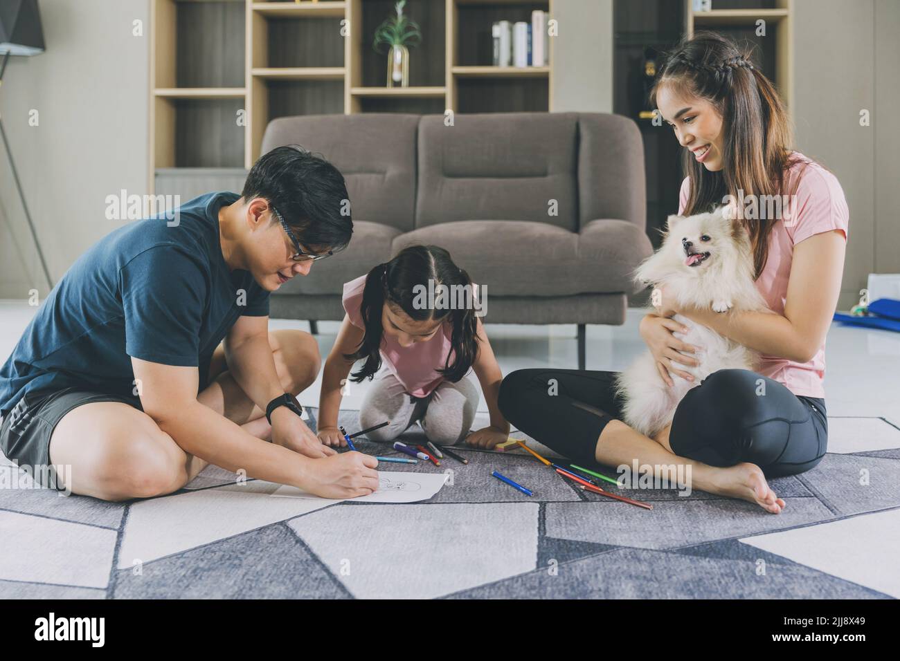 Une famille asiatique heureuse jouant avec un enfant et un animal de compagnie sympathique à la maison. Banque D'Images