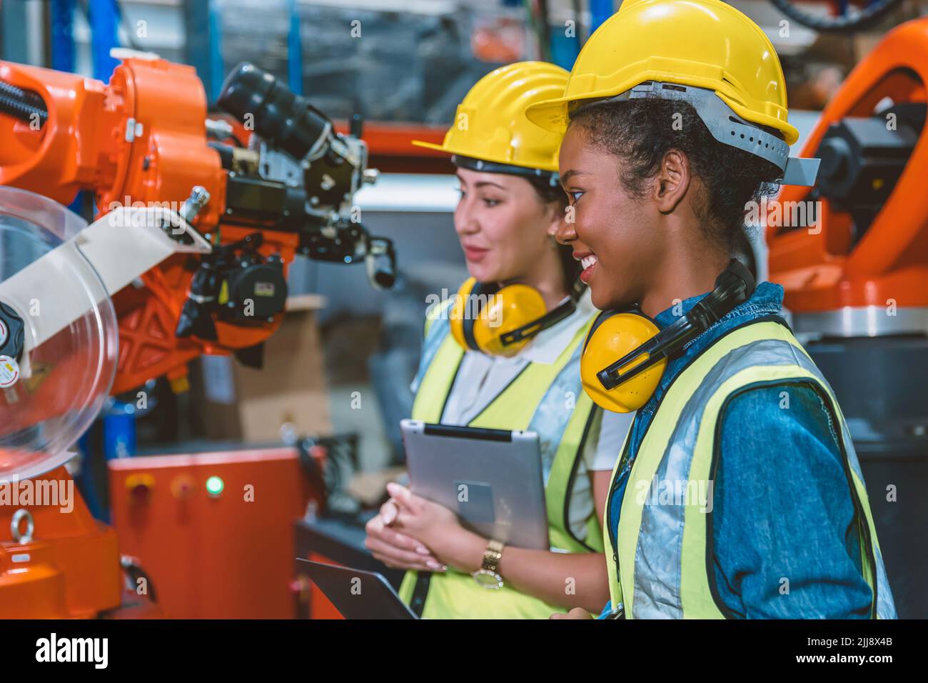 Une équipe de travail composée de femmes ingénieuses travaillant ensemble dans une usine de fabrication de machines modernes. Banque D'Images